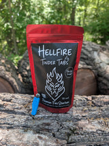 Red package of Hellfire Tinder Tabs on a log with trees in the background