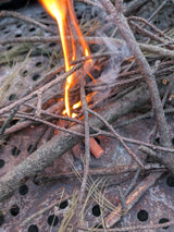 Fire burning through branches on a metal grill