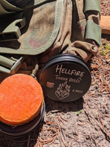 Hellfire Tinder Discs container with orange discs on a camouflage bag outdoors.